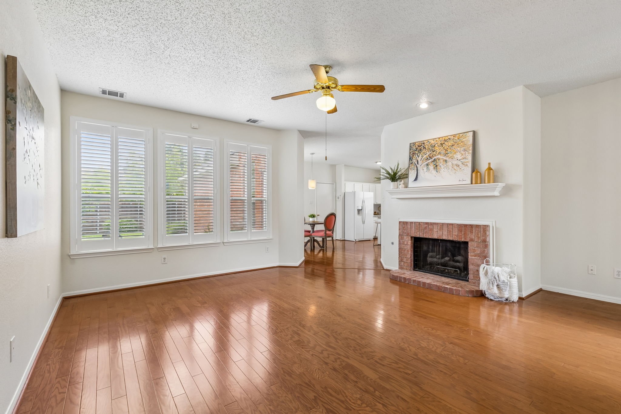 Family room at 7513 Caribbean Drive in Rowlett TX with wood floors plantation shutters and fireplace