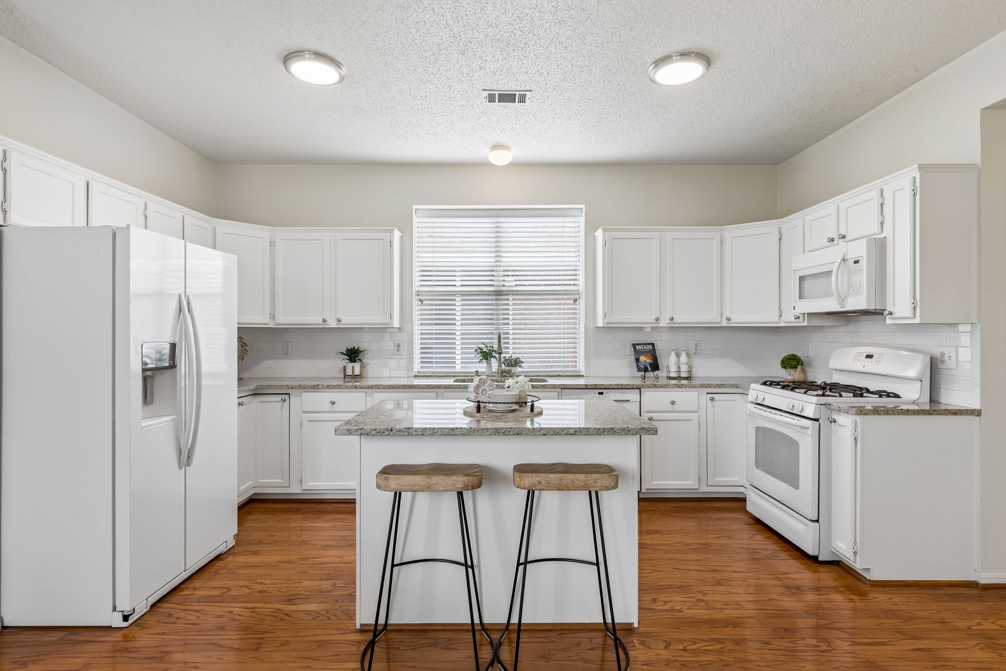 Kitchen at 7513 Caribbean Drive in Rowlett TX with white cabinets granite countertops island and subway tile backsplash