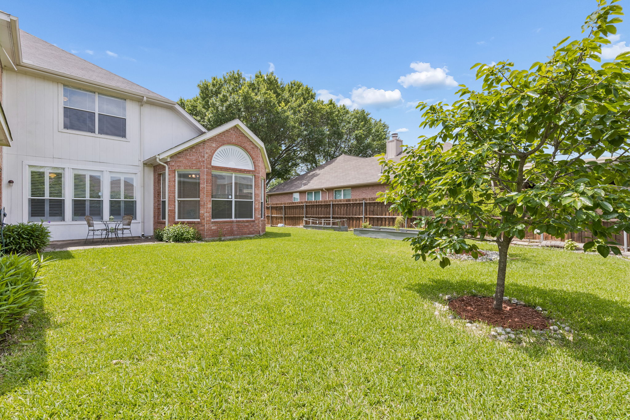 Backyard at 7513 Caribbean Drive in Rowlett TX with fruit trees raised garden beds and board on board cedar fence